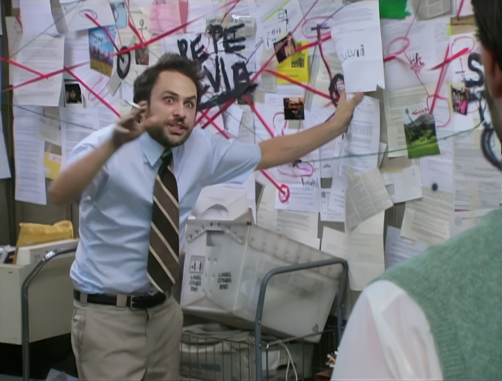 Charlie Day in front of a conspiracy wall covered in papers and red string
